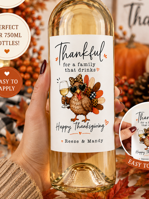 A hand holds a wine bottle decorated with a large, personalized Thanksgiving-themed label. The label features a cartoon turkey and the text 'Thankful for a family that drinks Happy Thanksgiving' with the names 'Reese & Mandy'.