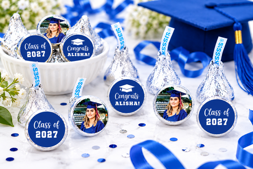 Graduation-themed Hershey's Kisses with personalized labels on a table with a blue cap and tassel.