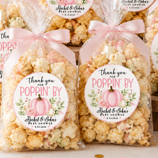 Six bags of gourmet popcorn arranged on a tabletop with pink roses, small pumpkins, and a decorative sign. Each bag is tied with a pink ribbon and has a round printed label that reads 'thank you POPPIN' BY Aesthetic & Alters'.