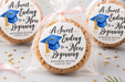 Graduation-themed cookies with personalized labels on a decorative table.