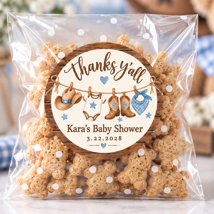 A clear plastic bag filled with bone-shaped cookies, sealed with a round personalized label that reads 'thanks y'all' and 'Kara's Baby Shower 3.22.