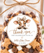 A clear cellophane gift bag filled with assorted baby shower mix, tied with a twine bow and labeled with a custom cow graphic and the text 'thank you for celebrating with us Katie & Baby Shower 05.12.