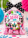 A clear cellophane bag of wrapped pink chocolates tied with a black-and-white polka dot bow, featuring a colorful round label with cartoon animals and the text 'Hope You Had A Wild 8th Birthday.' The bag is photographed on a decorated surface with tropical leaves and bright party props in the background.